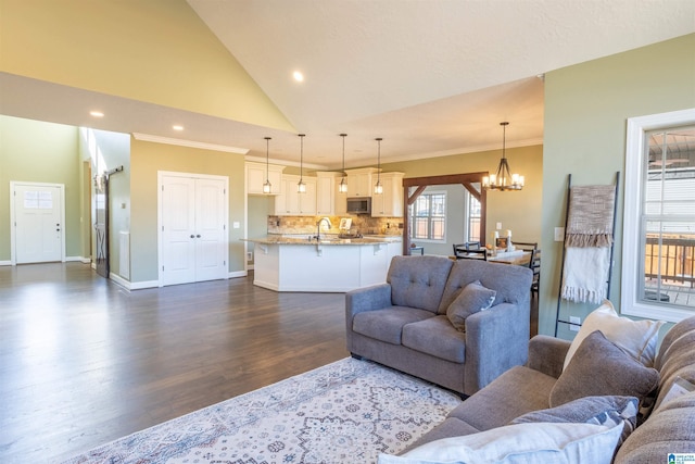 living room with high vaulted ceiling, an inviting chandelier, dark wood-type flooring, and sink