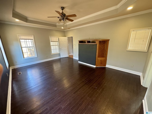 unfurnished room featuring a raised ceiling, crown molding, dark hardwood / wood-style flooring, and ceiling fan