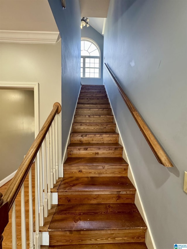 stairs featuring lofted ceiling and ornamental molding