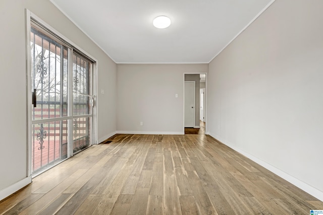 spare room with light wood-type flooring and crown molding