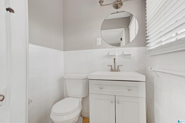 bathroom with vanity, toilet, and tile walls