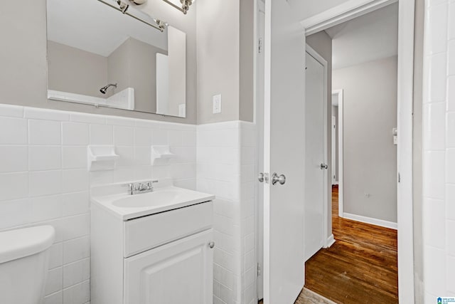 bathroom featuring vanity, wood-type flooring, tile walls, and toilet