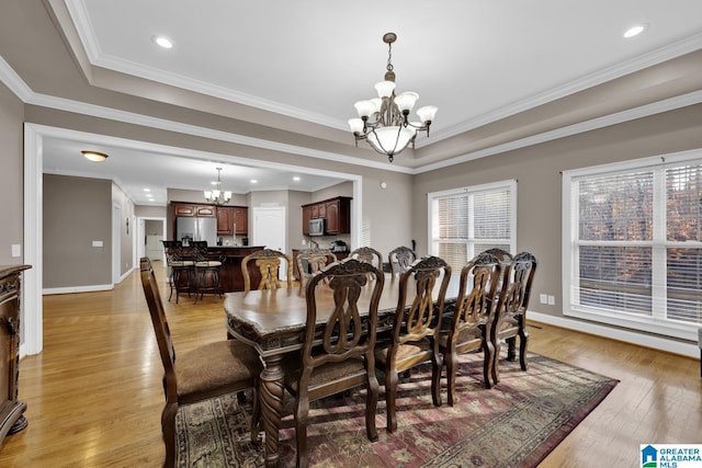 dining room with light hardwood / wood-style flooring, crown molding, a tray ceiling, and a chandelier