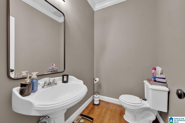 bathroom featuring hardwood / wood-style flooring, toilet, ornamental molding, and sink