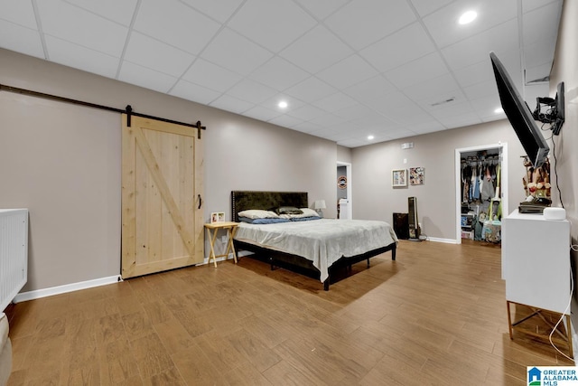 bedroom featuring a barn door, a spacious closet, a closet, and hardwood / wood-style floors