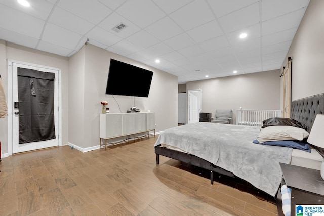 bedroom featuring a paneled ceiling, hardwood / wood-style floors, and a barn door