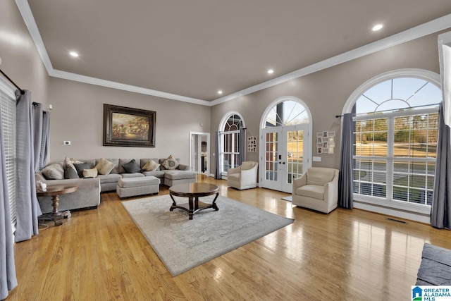 living room with crown molding, french doors, and light wood-type flooring