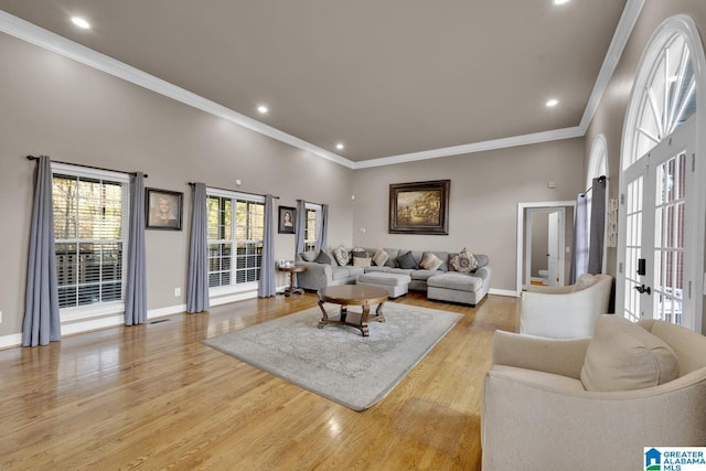 living room featuring french doors, crown molding, a towering ceiling, and light hardwood / wood-style flooring