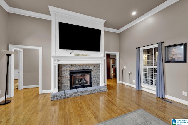 unfurnished living room featuring a stone fireplace, crown molding, and light hardwood / wood-style floors