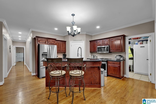 kitchen with a kitchen island with sink, a kitchen breakfast bar, ornamental molding, a notable chandelier, and stainless steel appliances