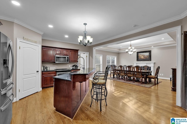 kitchen with hanging light fixtures, stainless steel appliances, an inviting chandelier, light hardwood / wood-style floors, and a breakfast bar