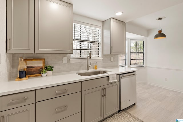 kitchen with dishwasher, sink, decorative backsplash, gray cabinets, and decorative light fixtures