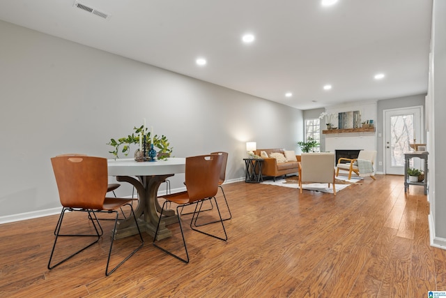 dining room featuring light wood-type flooring and a fireplace