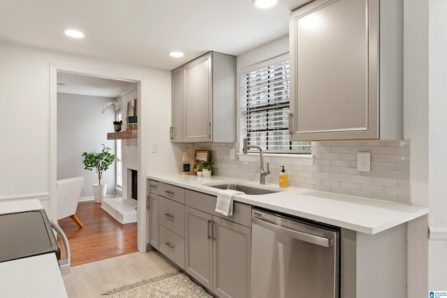 kitchen with stove, stainless steel dishwasher, light hardwood / wood-style floors, sink, and gray cabinets