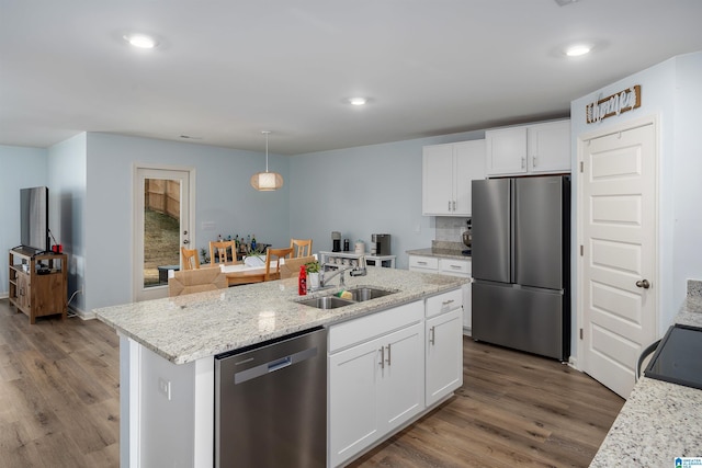 kitchen featuring hanging light fixtures, an island with sink, white cabinets, appliances with stainless steel finishes, and sink