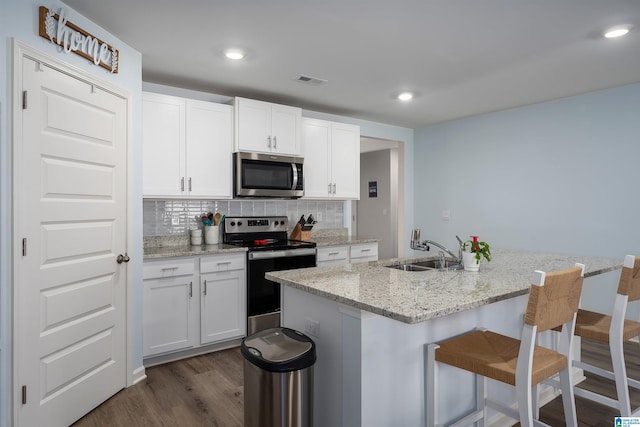 kitchen featuring stainless steel appliances, white cabinetry, backsplash, and sink