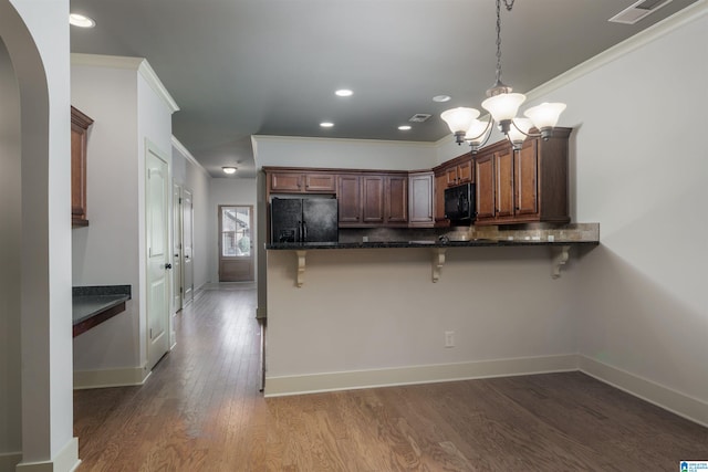 kitchen with a kitchen breakfast bar, kitchen peninsula, crown molding, decorative light fixtures, and black appliances