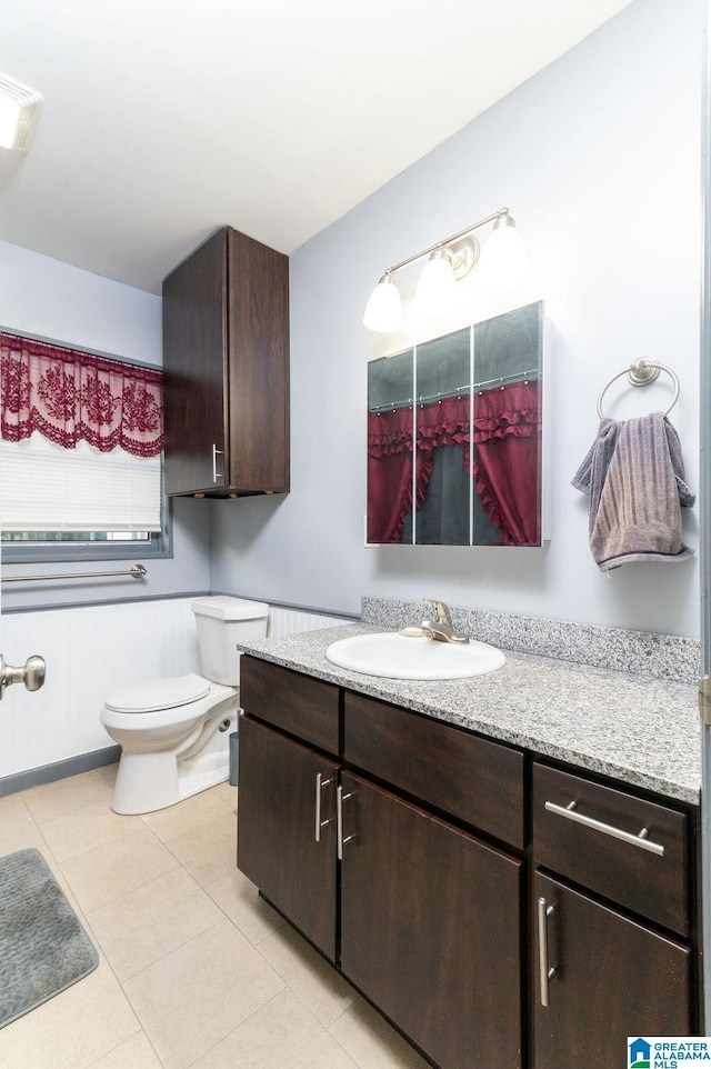 bathroom with toilet, vanity, and tile patterned floors