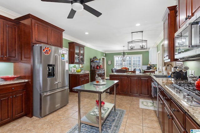 kitchen with decorative light fixtures, light stone countertops, ornamental molding, and appliances with stainless steel finishes