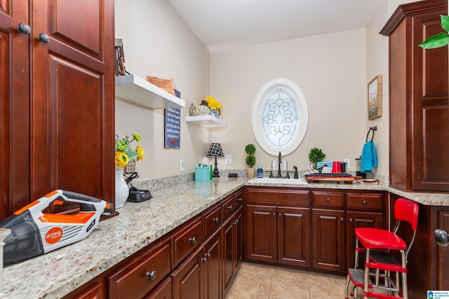 kitchen featuring light stone countertops, light tile patterned floors, kitchen peninsula, and sink