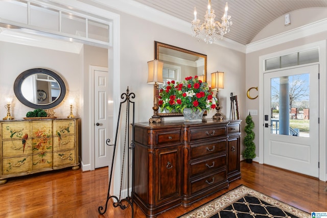 foyer entrance with crown molding, hardwood / wood-style floors, a chandelier, and vaulted ceiling