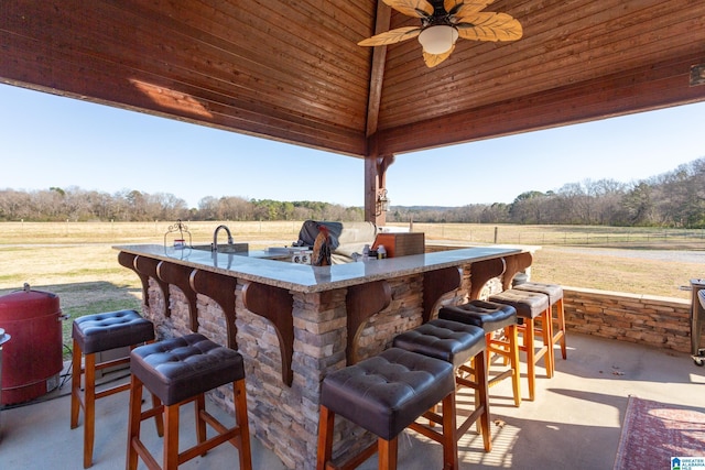 view of patio / terrace featuring exterior bar, a rural view, area for grilling, and ceiling fan