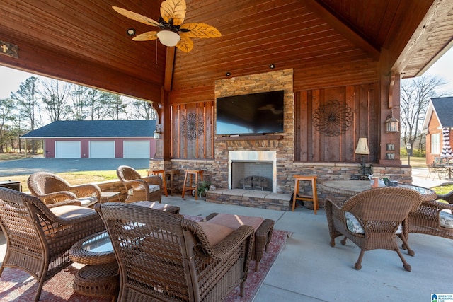 view of patio / terrace featuring an outdoor structure, an outdoor stone fireplace, ceiling fan, a gazebo, and a garage