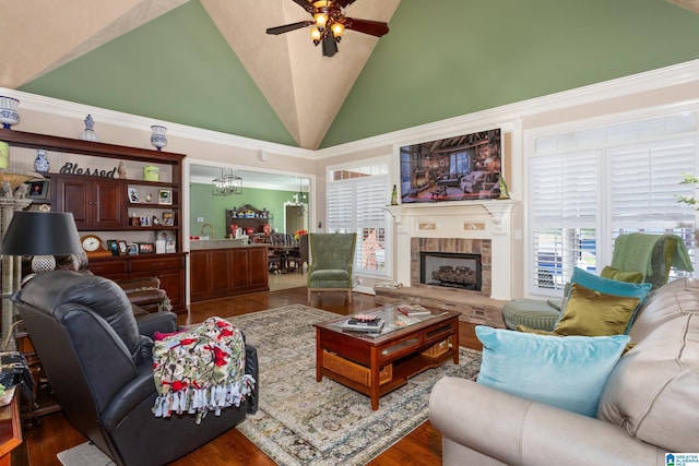 living room featuring ceiling fan with notable chandelier, a stone fireplace, plenty of natural light, and high vaulted ceiling