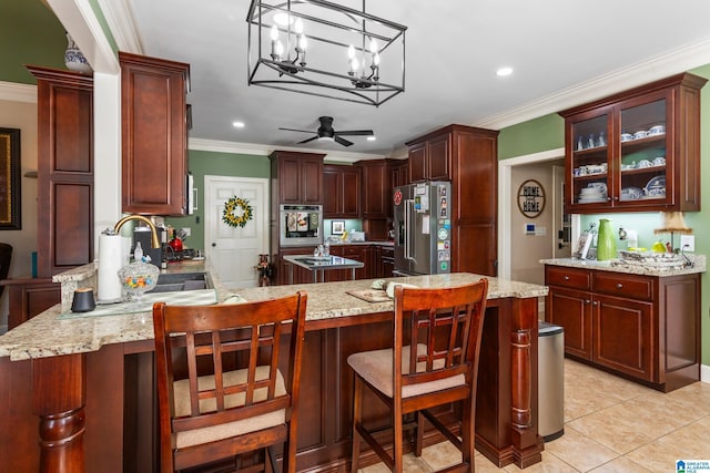 kitchen with stainless steel appliances, decorative light fixtures, light tile patterned floors, ceiling fan with notable chandelier, and ornamental molding