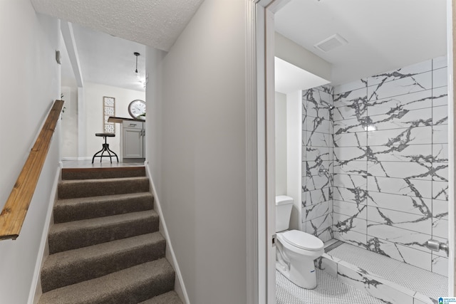 stairs featuring a textured ceiling