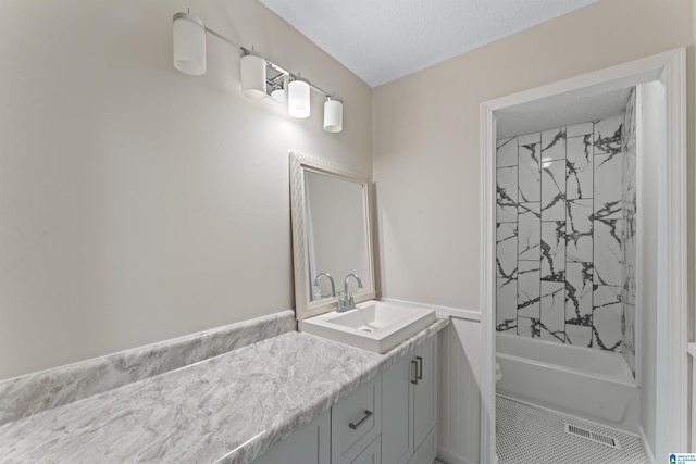 full bathroom with vanity, toilet, a textured ceiling, and tiled shower / bath combo