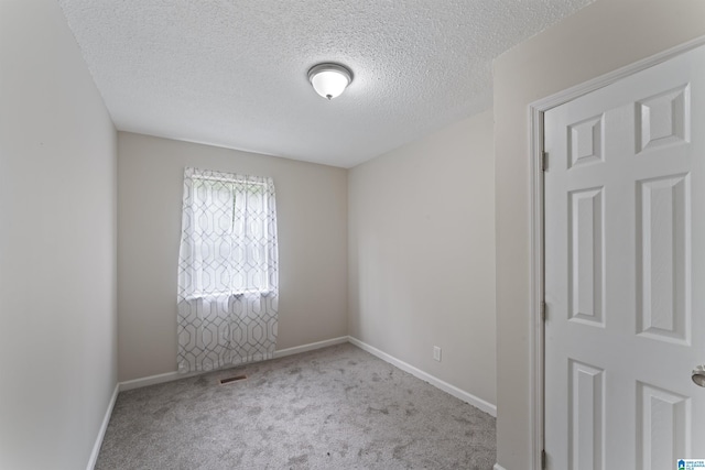 empty room with light colored carpet and a textured ceiling