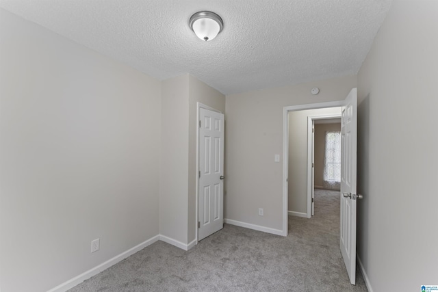 unfurnished bedroom featuring a textured ceiling and light carpet