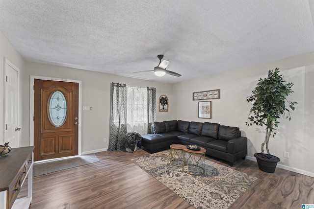 living room with a textured ceiling, ceiling fan, and dark wood-type flooring