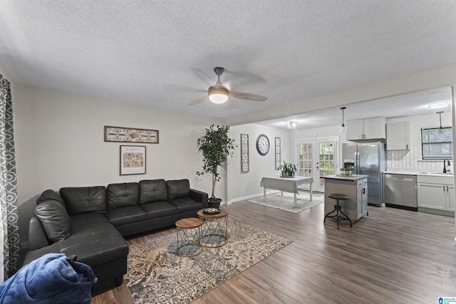 living room featuring french doors, sink, ceiling fan, dark hardwood / wood-style floors, and a textured ceiling