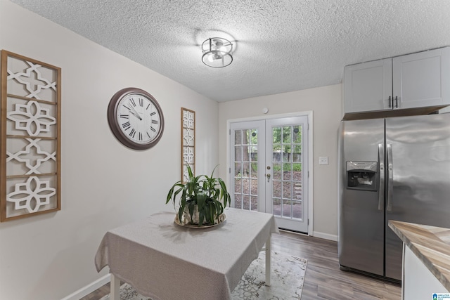 dining room featuring light wood-type flooring, a textured ceiling, and french doors