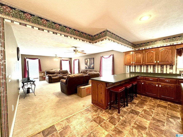 kitchen featuring a breakfast bar, dark carpet, a textured ceiling, and ceiling fan