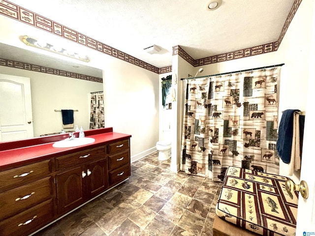 bathroom with vanity, a textured ceiling, and toilet