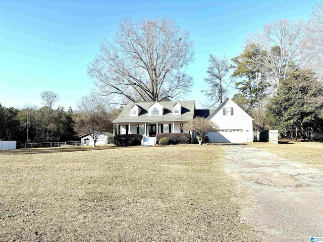 cape cod home with covered porch, a front yard, and a garage