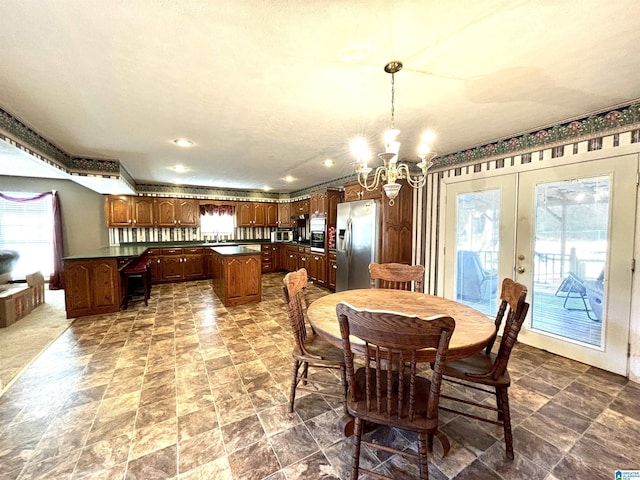 dining room featuring a textured ceiling, french doors, plenty of natural light, and an inviting chandelier