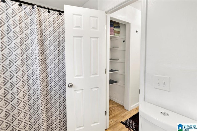 bathroom with toilet, wood-type flooring, and walk in shower