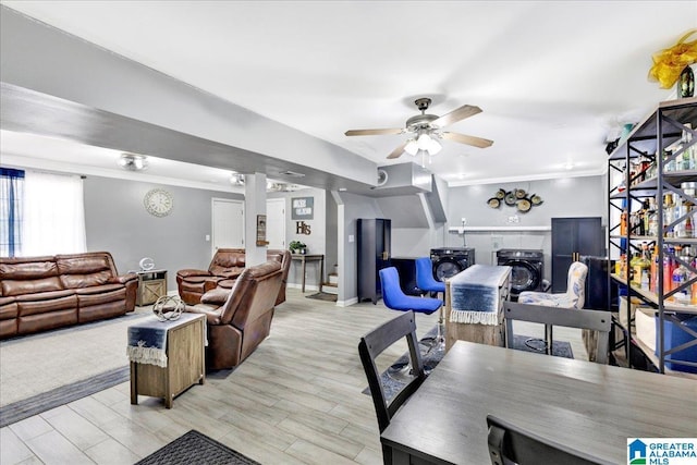 living room featuring a wood stove, ceiling fan, crown molding, and light hardwood / wood-style floors