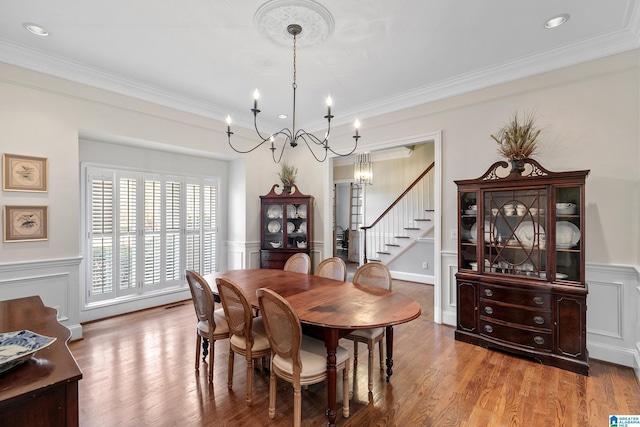 dining area featuring an inviting chandelier, ornamental molding, and hardwood / wood-style flooring