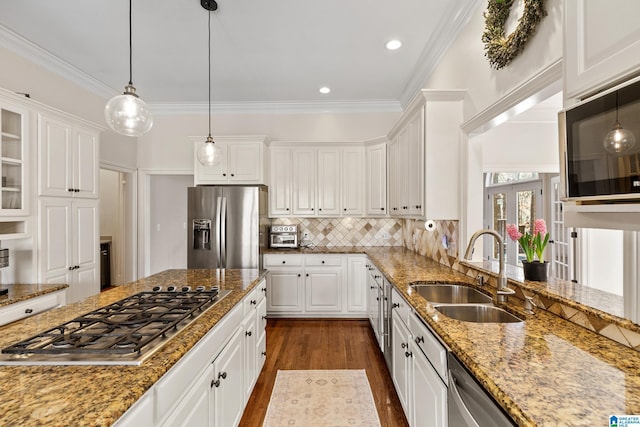 kitchen with appliances with stainless steel finishes, light stone counters, sink, pendant lighting, and white cabinetry