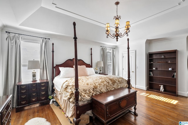 bedroom featuring an inviting chandelier, crown molding, dark wood-type flooring, and a tray ceiling