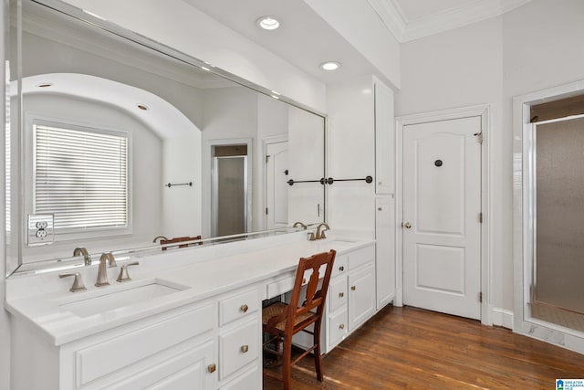 bathroom with ornamental molding, vanity, hardwood / wood-style flooring, and a shower with shower door