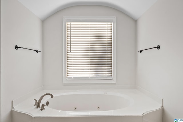 bathroom with a bathing tub and vaulted ceiling