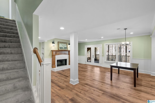 interior space featuring hardwood / wood-style floors, french doors, a brick fireplace, built in shelves, and a chandelier