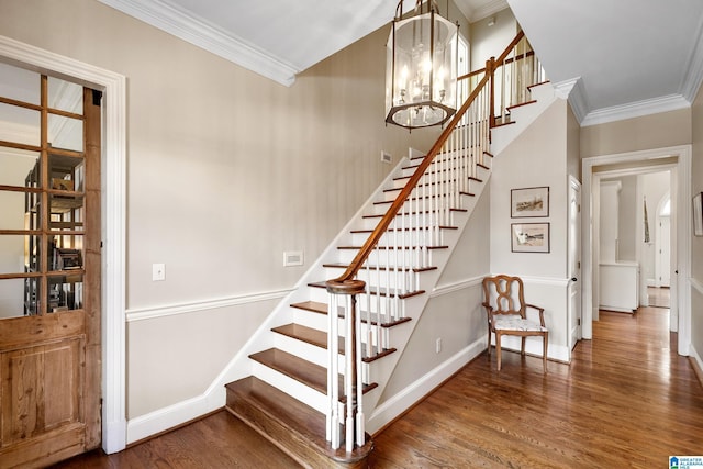 stairs featuring wood-type flooring, ornamental molding, and a notable chandelier