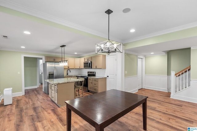 kitchen with a center island, stainless steel appliances, decorative light fixtures, and ornamental molding